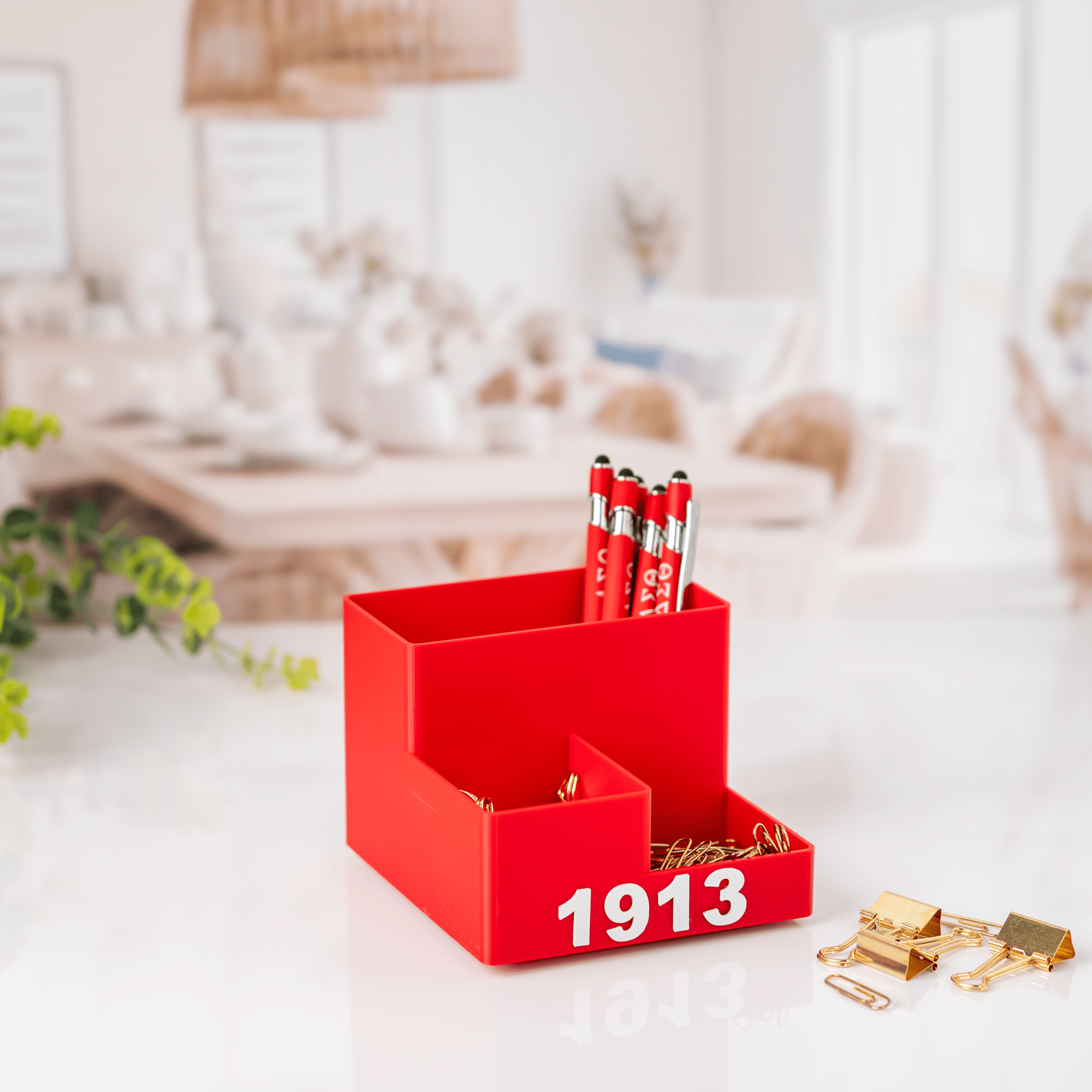 Delta Sigma Theta crimson desk organizer filled with DST pens and gold clips on bright office desk