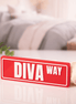 Customizable DST street sign desk display reading Diva Way in crimson and white on white surface