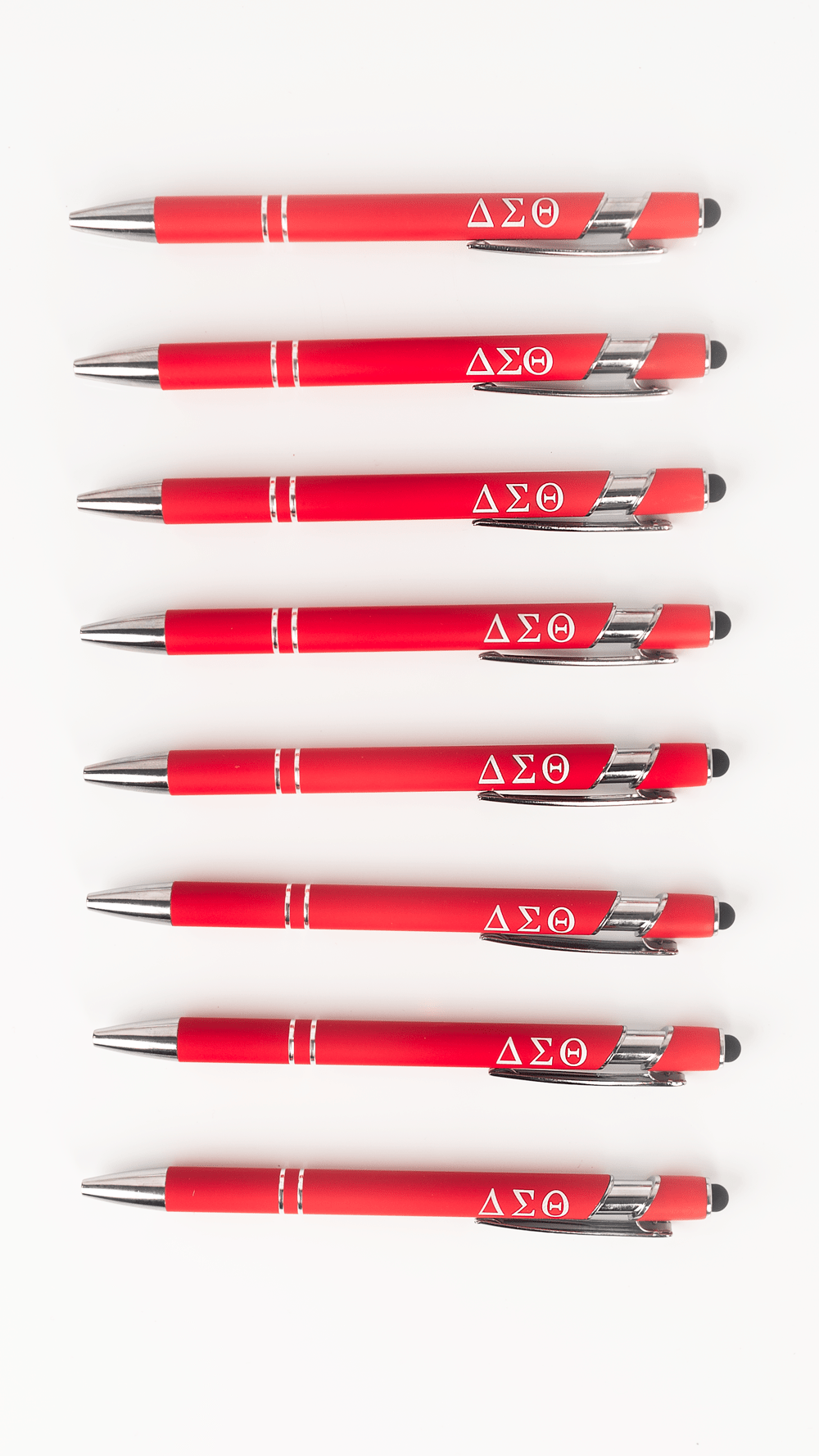 Seven Delta Sigma Theta crimson stylus ballpoint pens with Greek letters lined up on white background