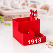 DST 1913 crimson desk organizer filled with Greek letter pens and gold paper clips on bright desk