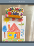 A colorful children's crayon drawing of a house and trees magnetically clipped to a stainless steel refrigerator, with a laser-engraved wooden sign reading 'look what I made!' resting on top. The image is framed with a dark blue border containing the text 'LASER ENGRAVED'.