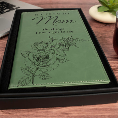 Angled view of green Notes to My Mom keepsake journal showing engraved floral artwork, script lettering, and stitched edges.