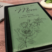 Close-up of green Notes to My Mom leatherette journal featuring engraved script lettering and detailed rose illustrations.