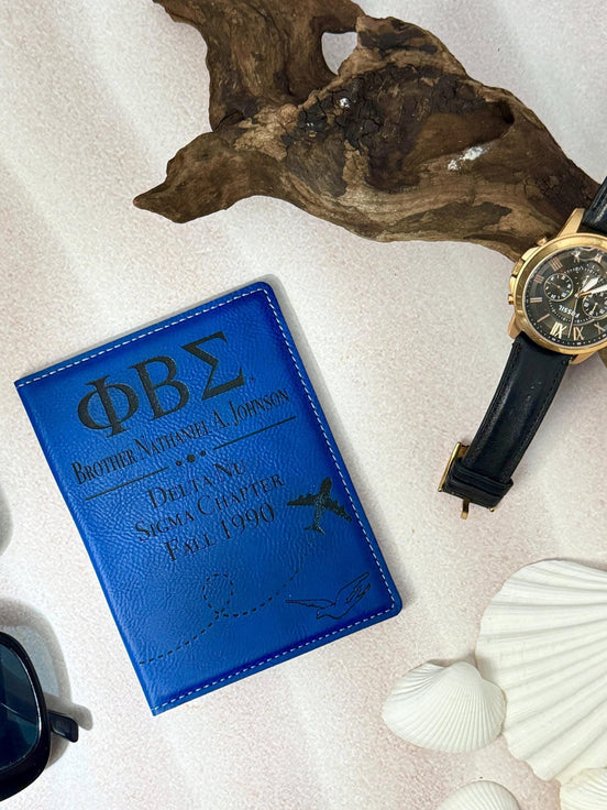 Royal blue PBS passport holder laser engraved with Greek letters brother name and chapter on white surface