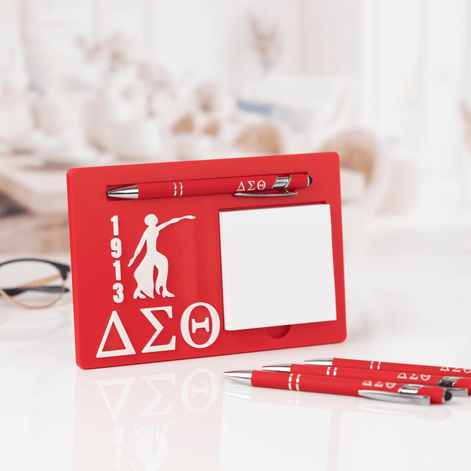 Delta Sigma Theta sticky note desk display with pen on white desk with glasses and extra pens nearby
