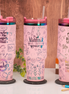 Three personalized pink teacher tumblers with engraved rainbow designs and handles